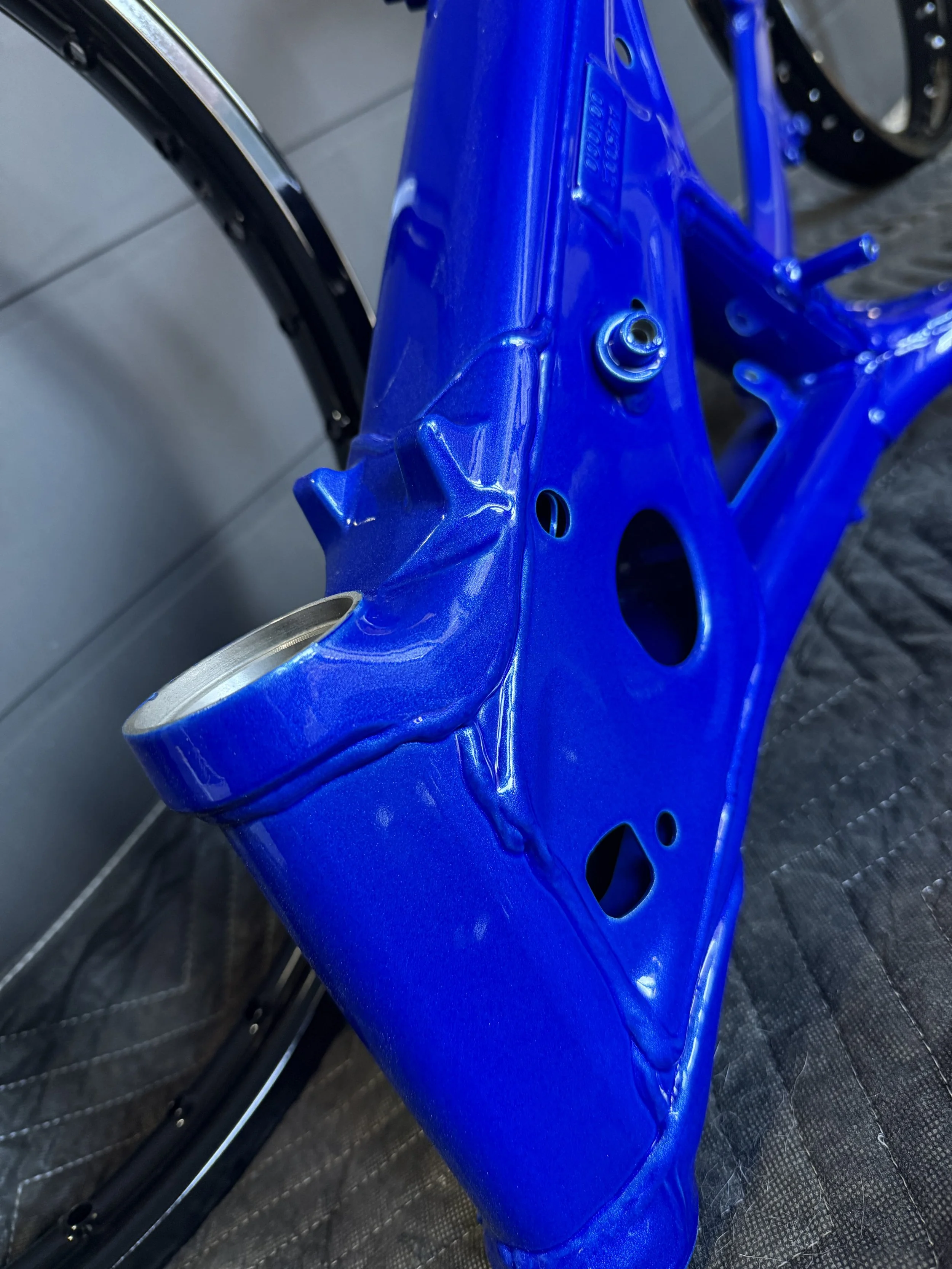 Close-up of a shiny blue bicycle frame with a rear wheel attached.