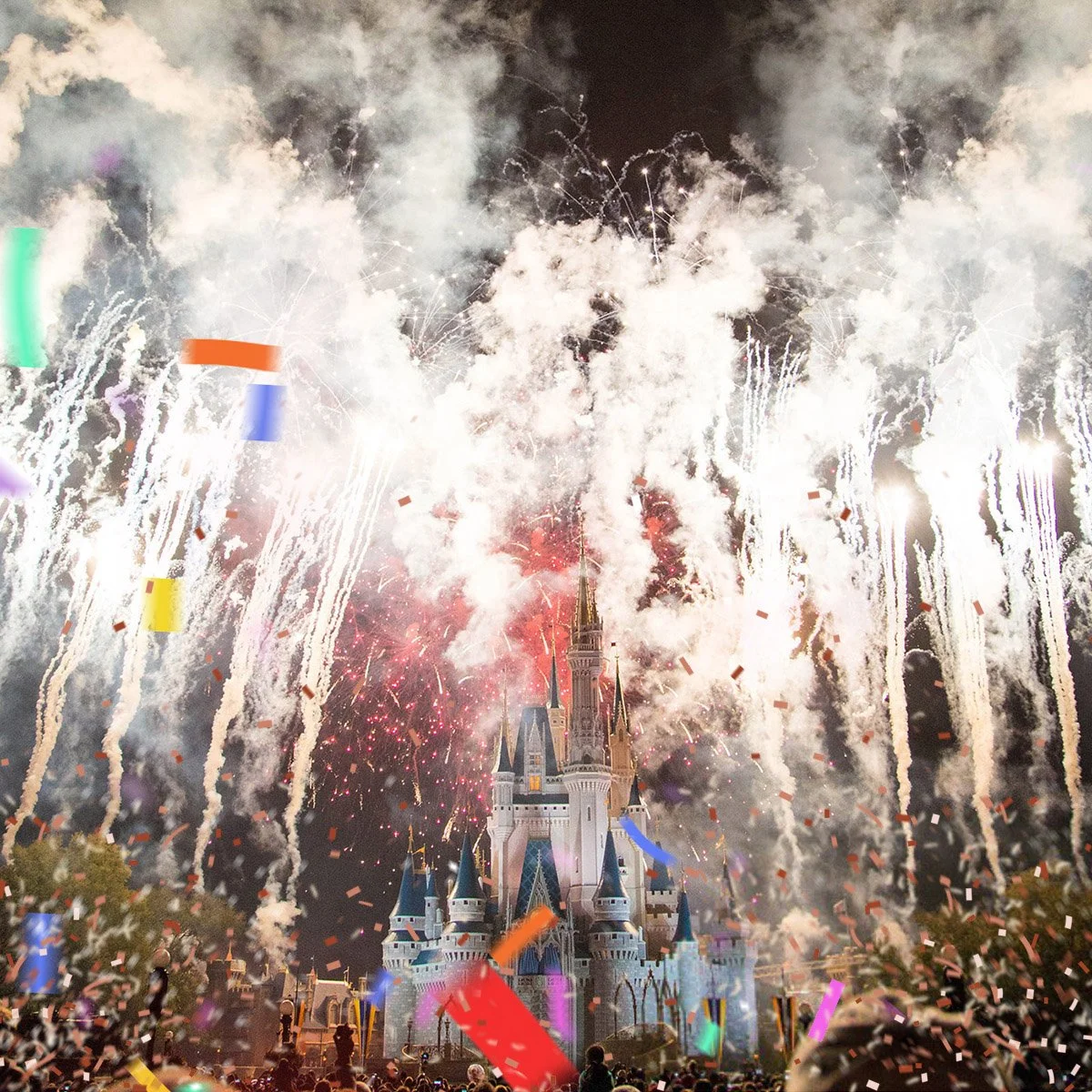 Fireworks display over a castle at night with colorful confetti falling.