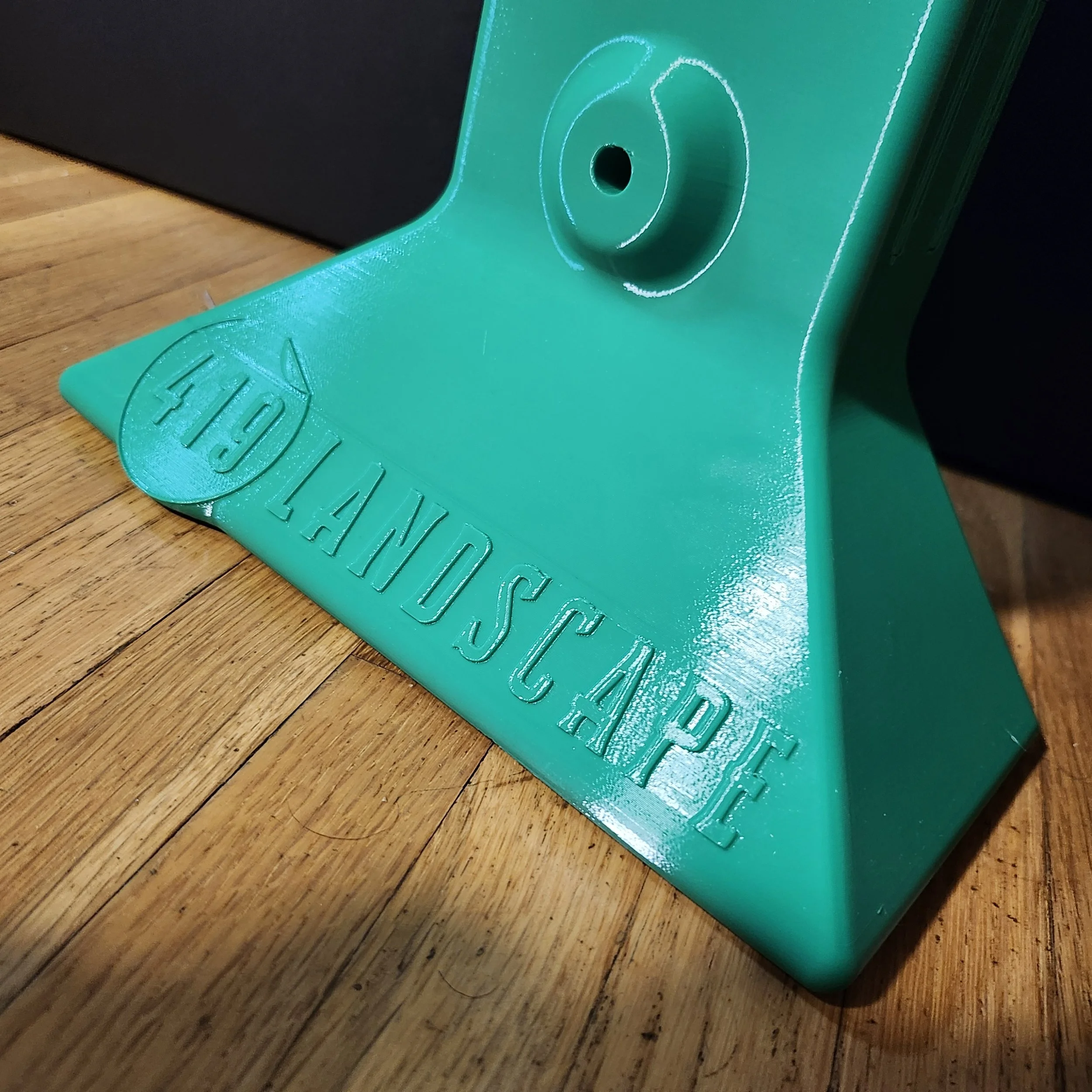 A turquoise plastic board with embossed text and a centered hole, placed on a wooden surface.
