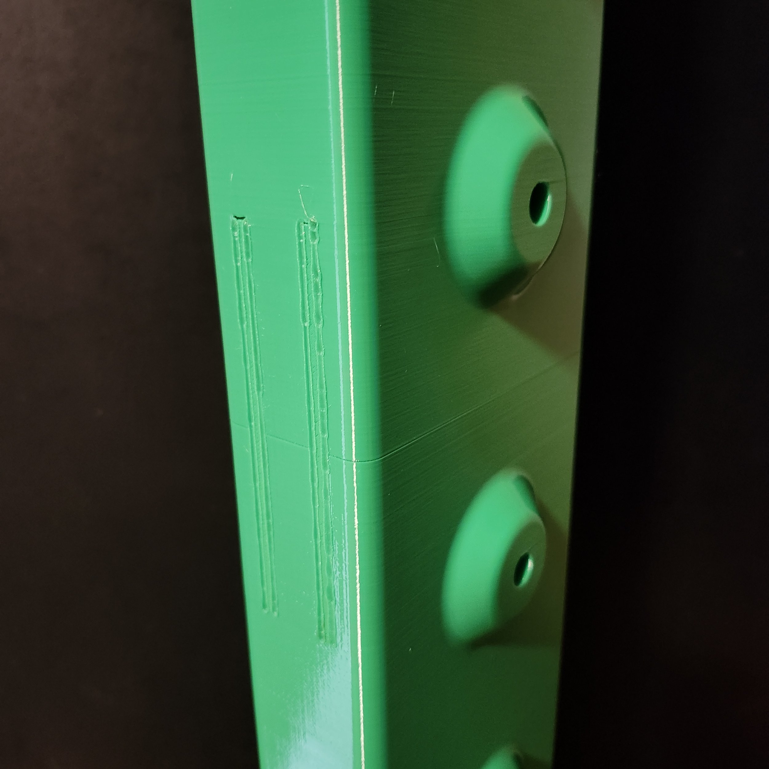 A close-up of a green electronic device or appliance with a circular knob or button and some small holes, set against a dark background.