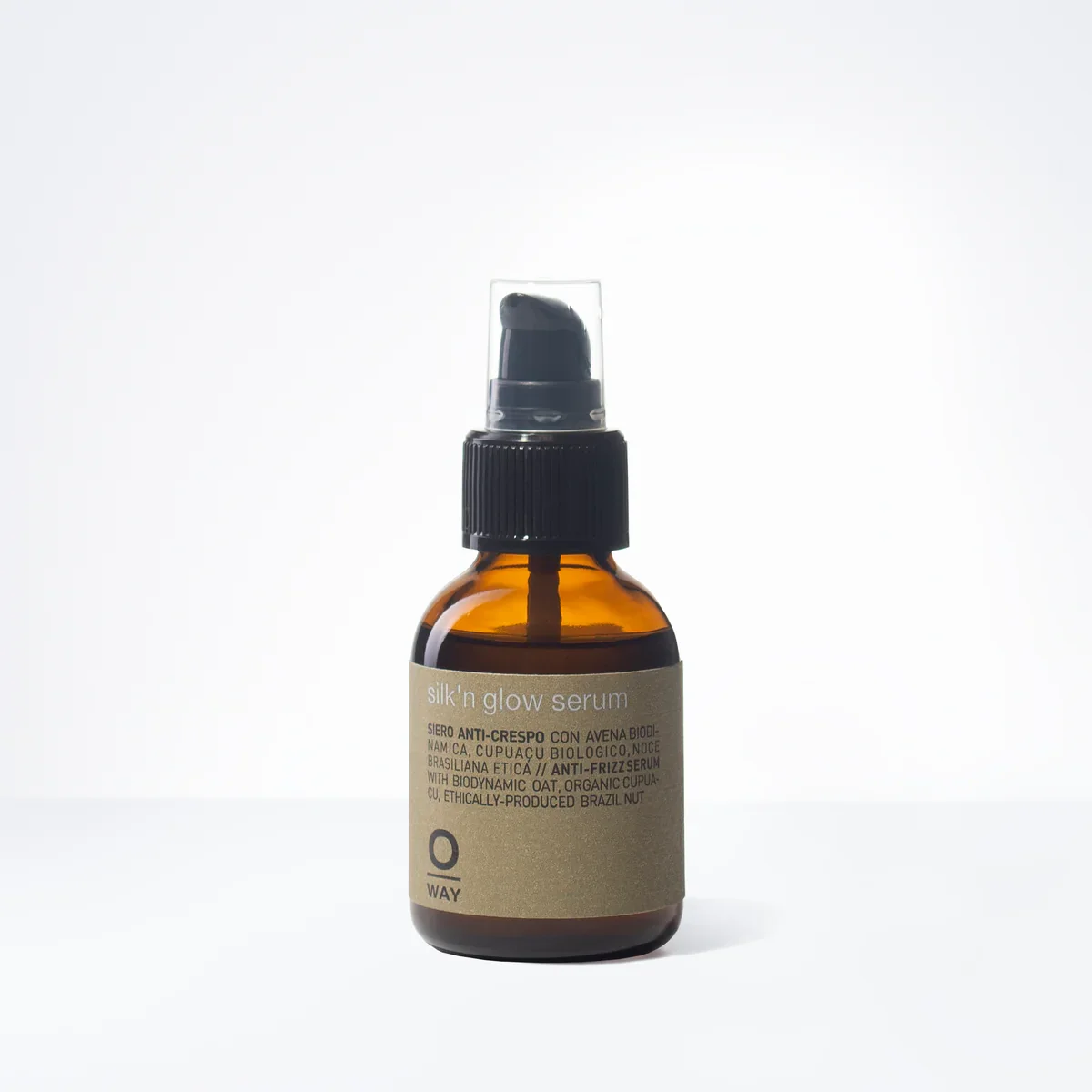Amber glass bottle with black spray nozzle containing Silk'n Glow Serum, labeled with product description and ingredients on beige paper label.