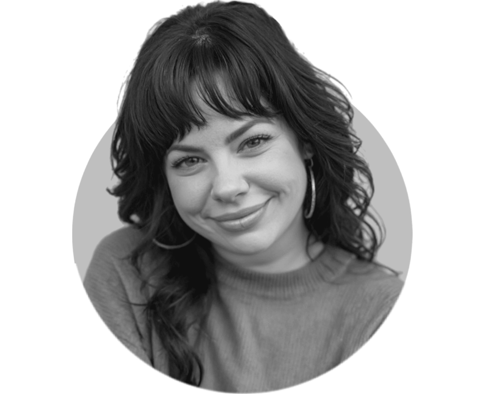 Black and white photo of a woman with shoulder-length wavy hair, smiling, wearing hoop earrings, and looking at the camera.