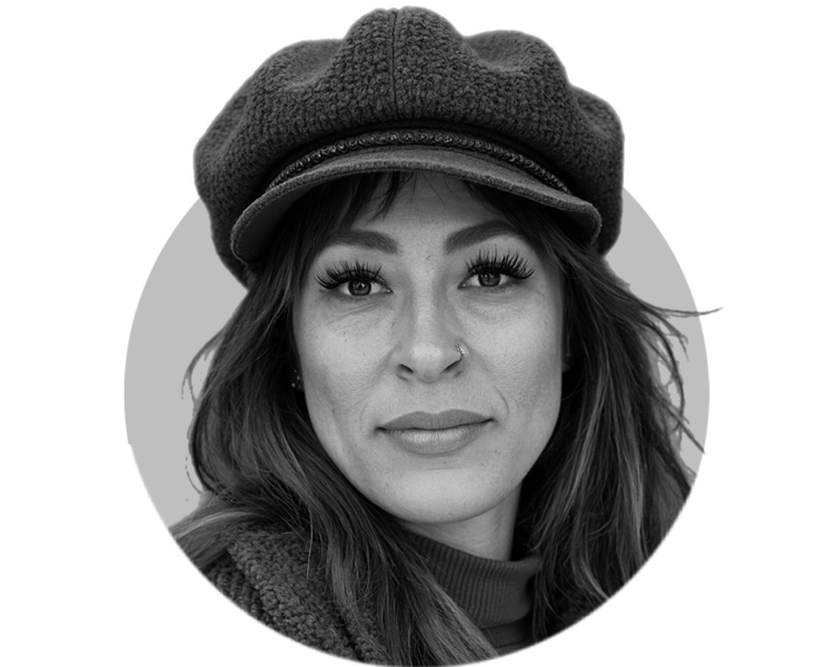 A woman with long hair wearing a textured beret and a jacket, looking directly at the camera, in black and white