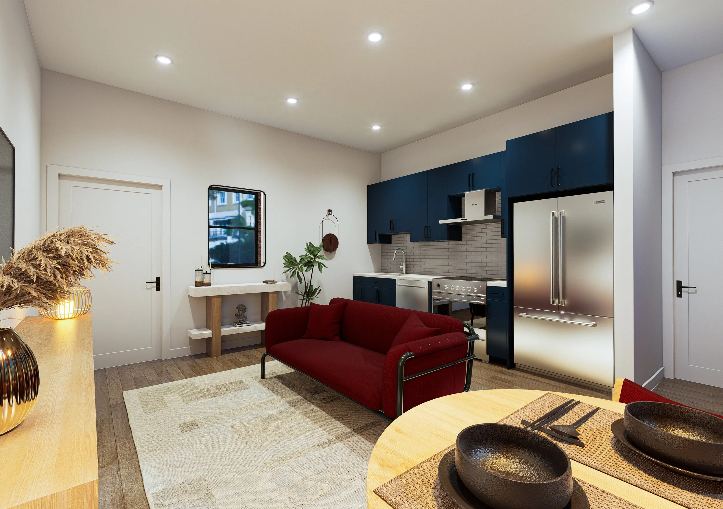 Modern open-concept kitchen with blue cabinets, stainless steel appliances, a white backsplash, and a window overlooking greenery. Adjacent living area with a red sofa, beige rug, and decorative plants.