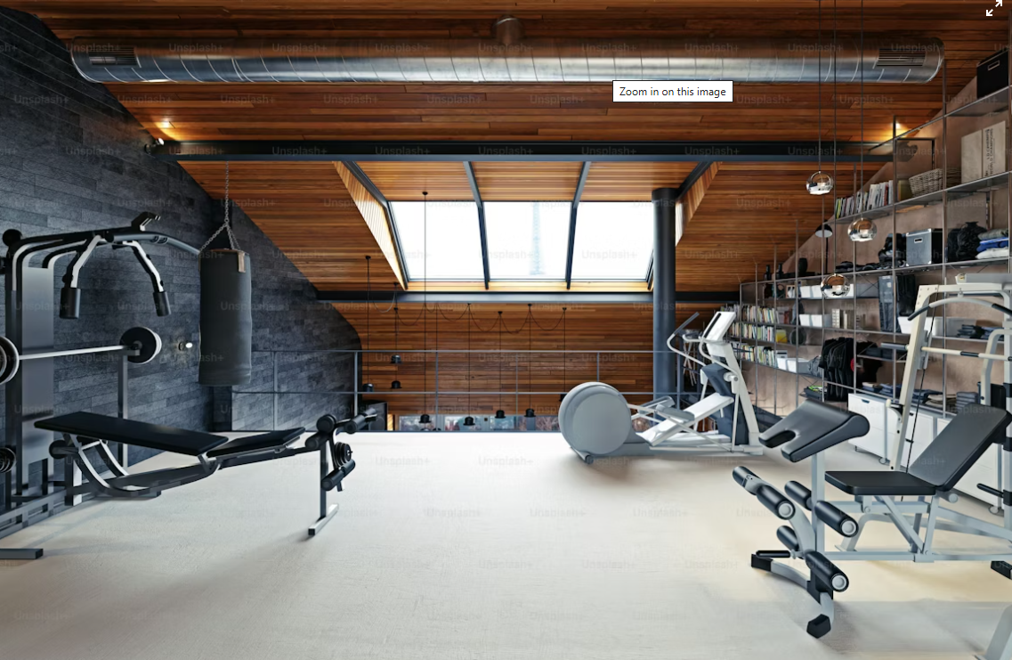 Modern home gym with workout equipment, including a weight bench, punching bag, elliptical trainer, and weight machine, with wooden ceiling, large skylight, and open shelving with books and storage items.