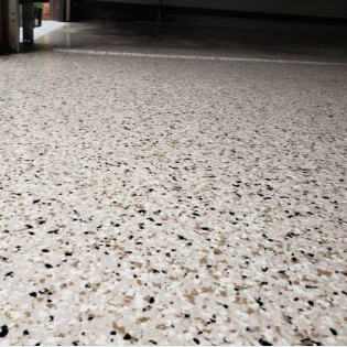 Close-up of a speckled terrazzo floor with small black, white, and beige chips.