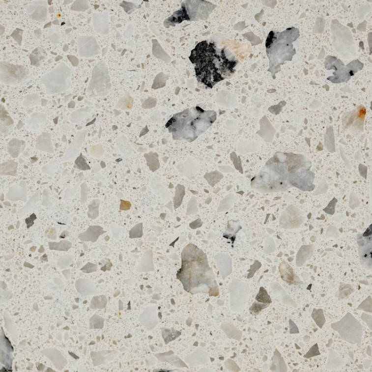 Close-up of a speckled terrazzo countertop with various chip sizes and colors, primarily white and gray with some black and brown pieces.
