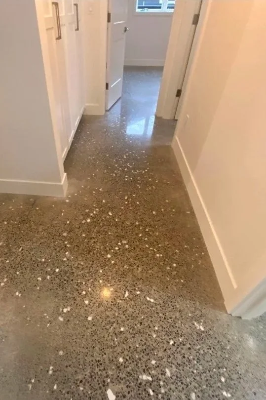 A hallway with a polished concrete floor that has white paint splatters across it.