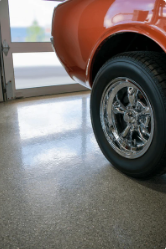 Close-up of a vehicle's tire and wheel inside a garage with a concrete floor.