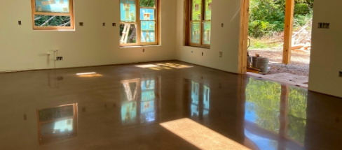 Empty room with hardwood floors, large windows, and an open door leading outside.