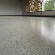 Empty indoor space with a smooth, polished floor and large windows showing trees outside.