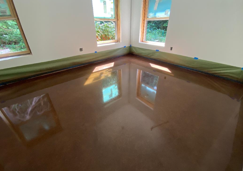 Empty room with multiple windows and a freshly polished hardwood floor, reflecting the windows and outside scene.