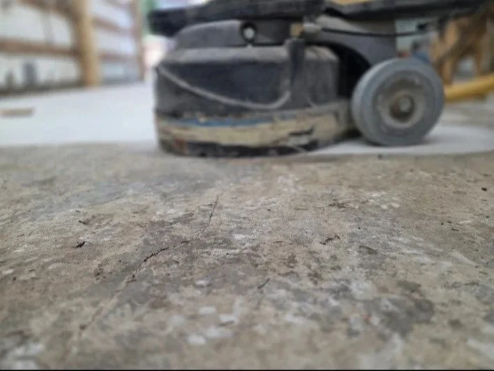 Close-up of a floor grinding machine on a concrete surface in a construction site.