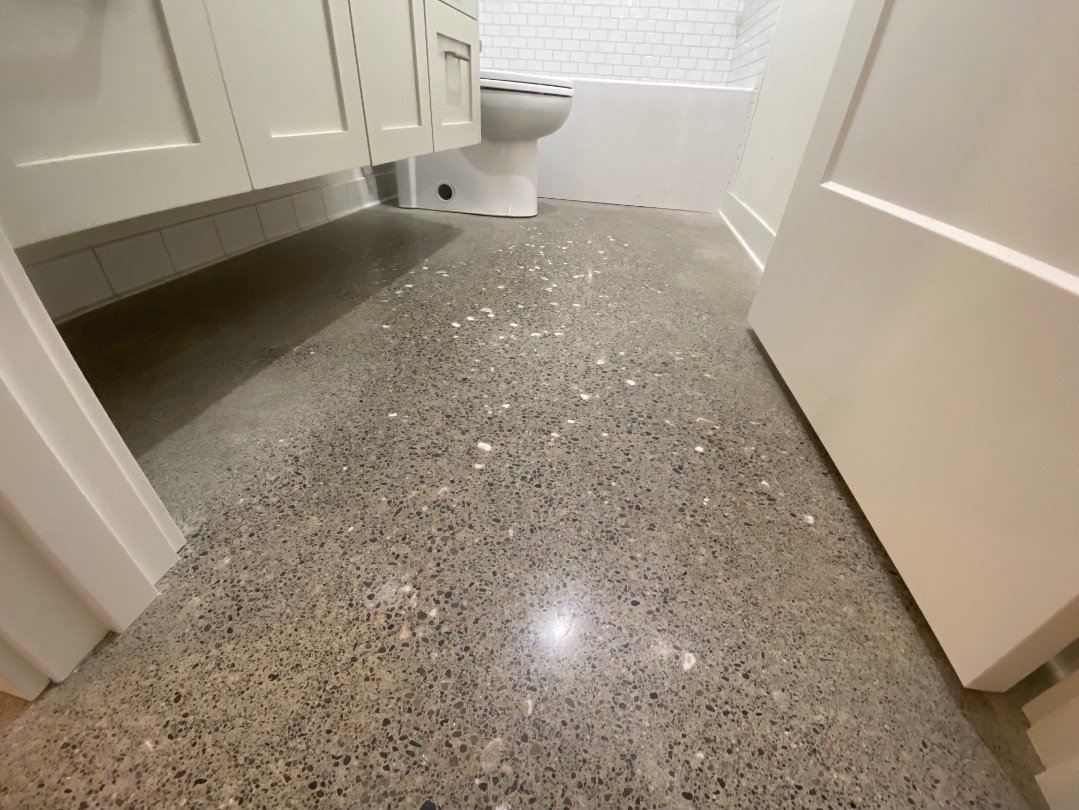 A bathroom with terrazzo flooring, white cabinets, and a toilet.