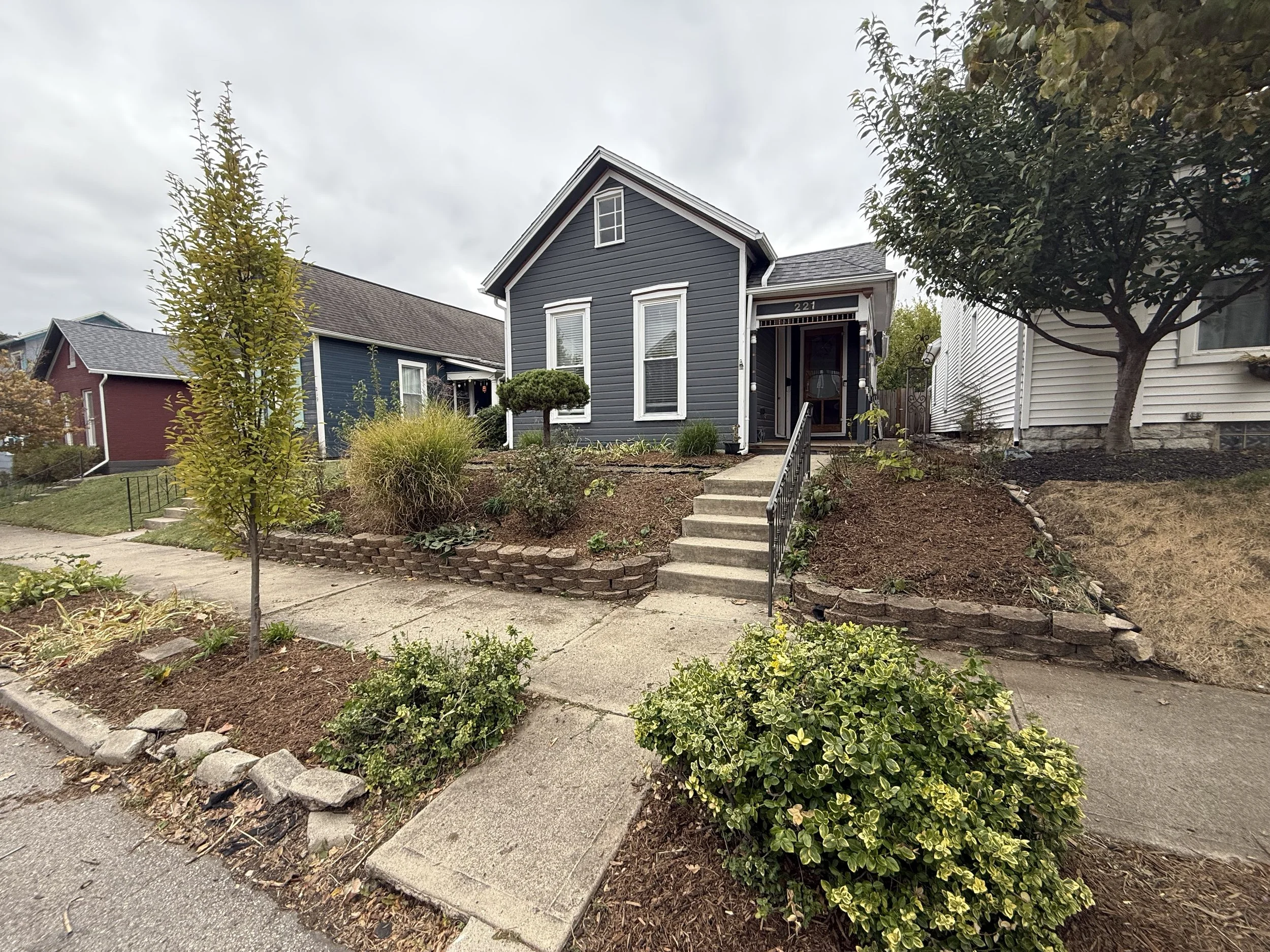 Front yard of a gray house after land-cleanup in Dayton, Ohio. Surrounded by native landscaped plants and trees.
