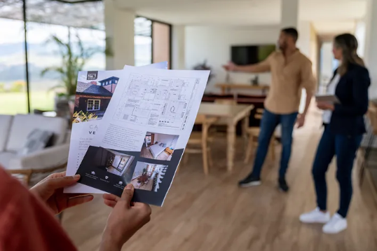 People looking at a real estate brochure inside a modern home