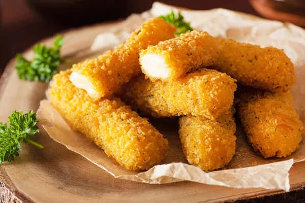 Fried cheese sticks on paper-lined wooden plate with parsley garnish.