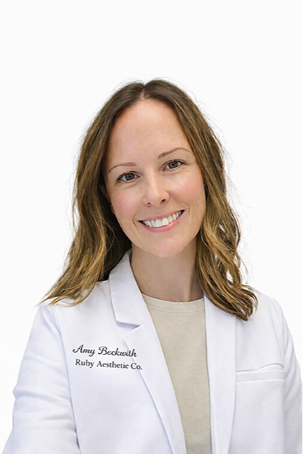 A woman with shoulder-length light brown hair wearing a white lab coat with name tag 'Amy Beckwirh, Ruby Aesthetic Co.' smiling at the camera.