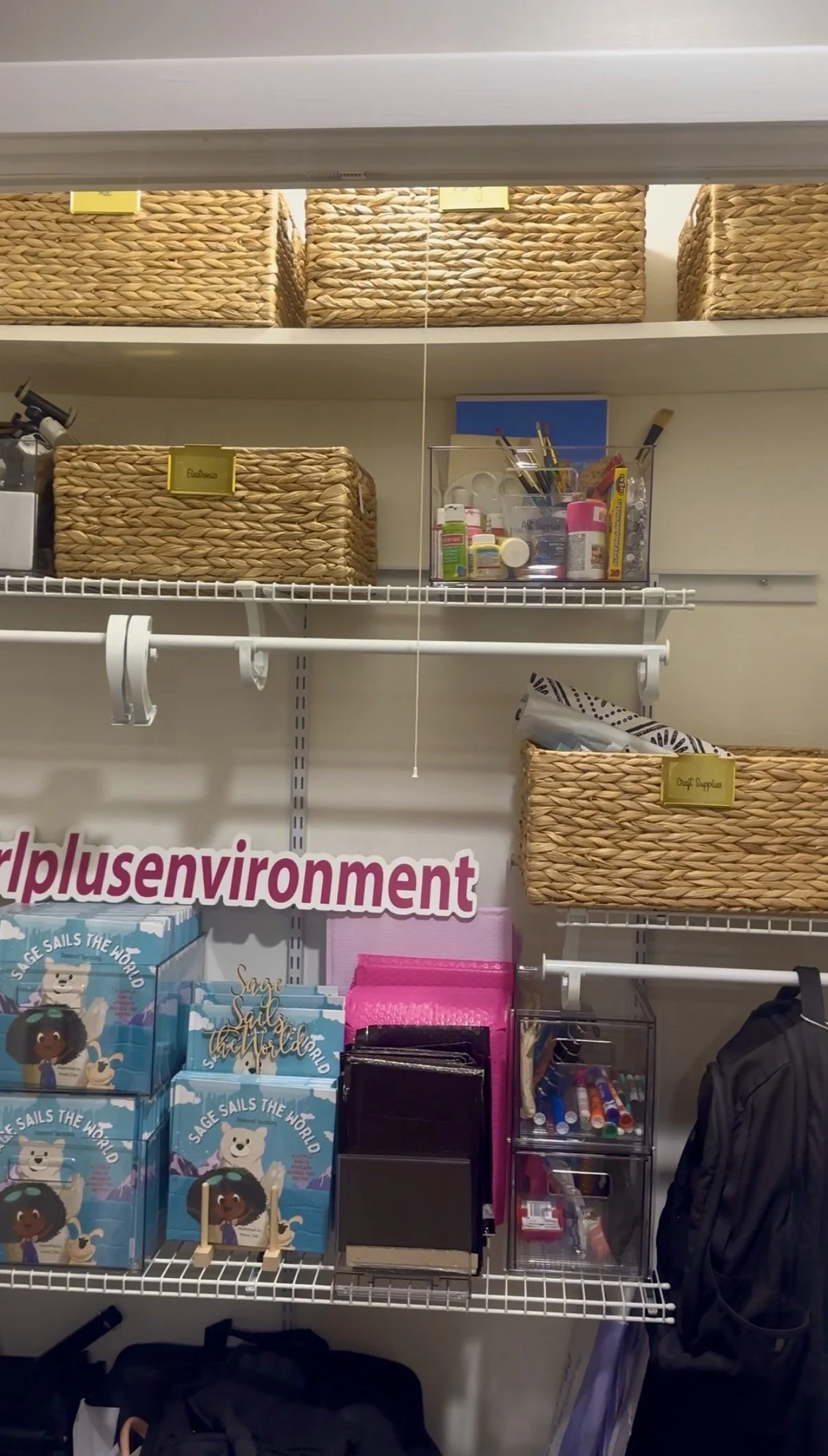Closet shelf with woven baskets, art supplies, and children's book titled "Sage Sails the World"