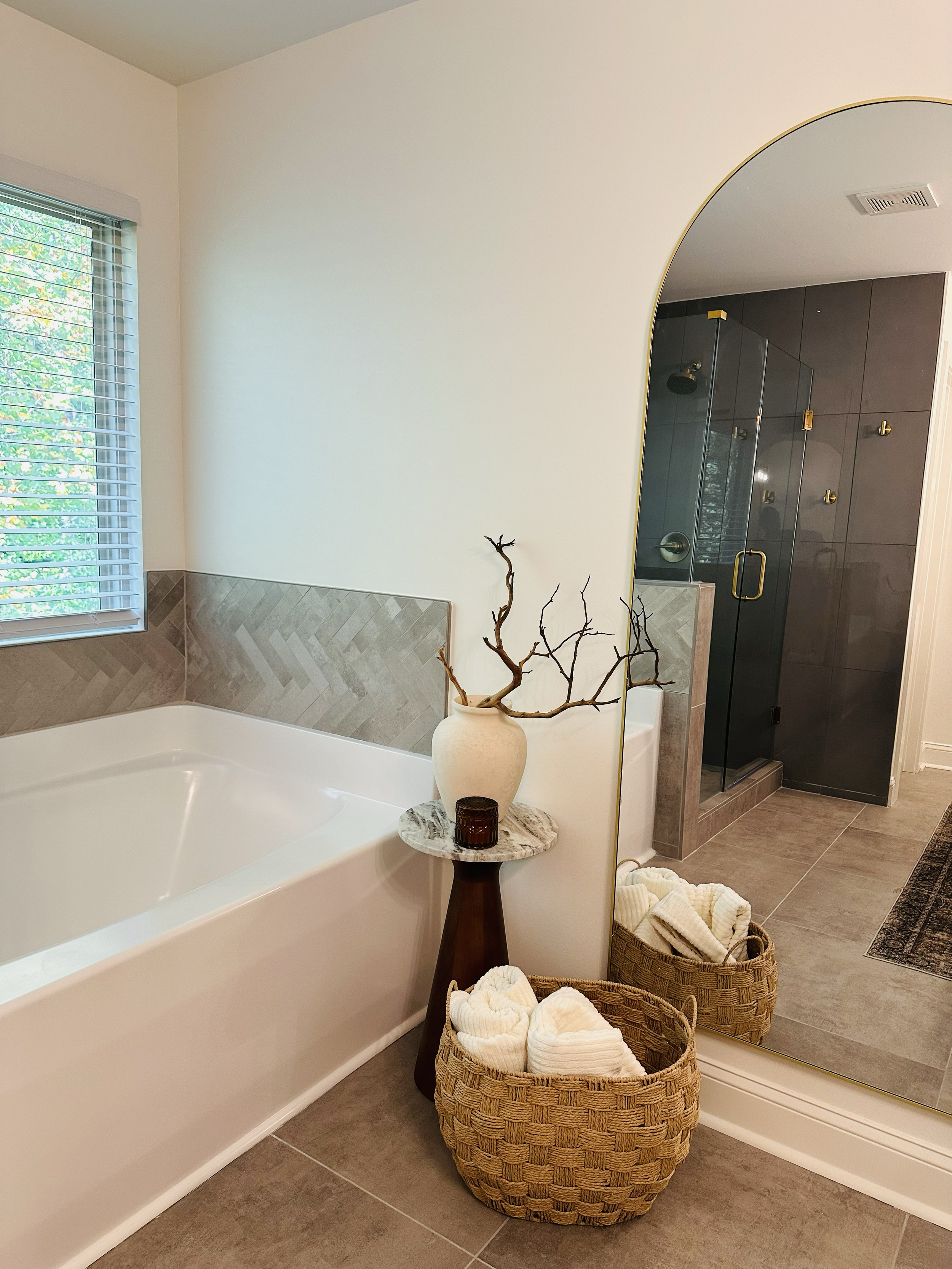 Bathroom with bathtub, mirror, shower, and decorative baskets with towels.