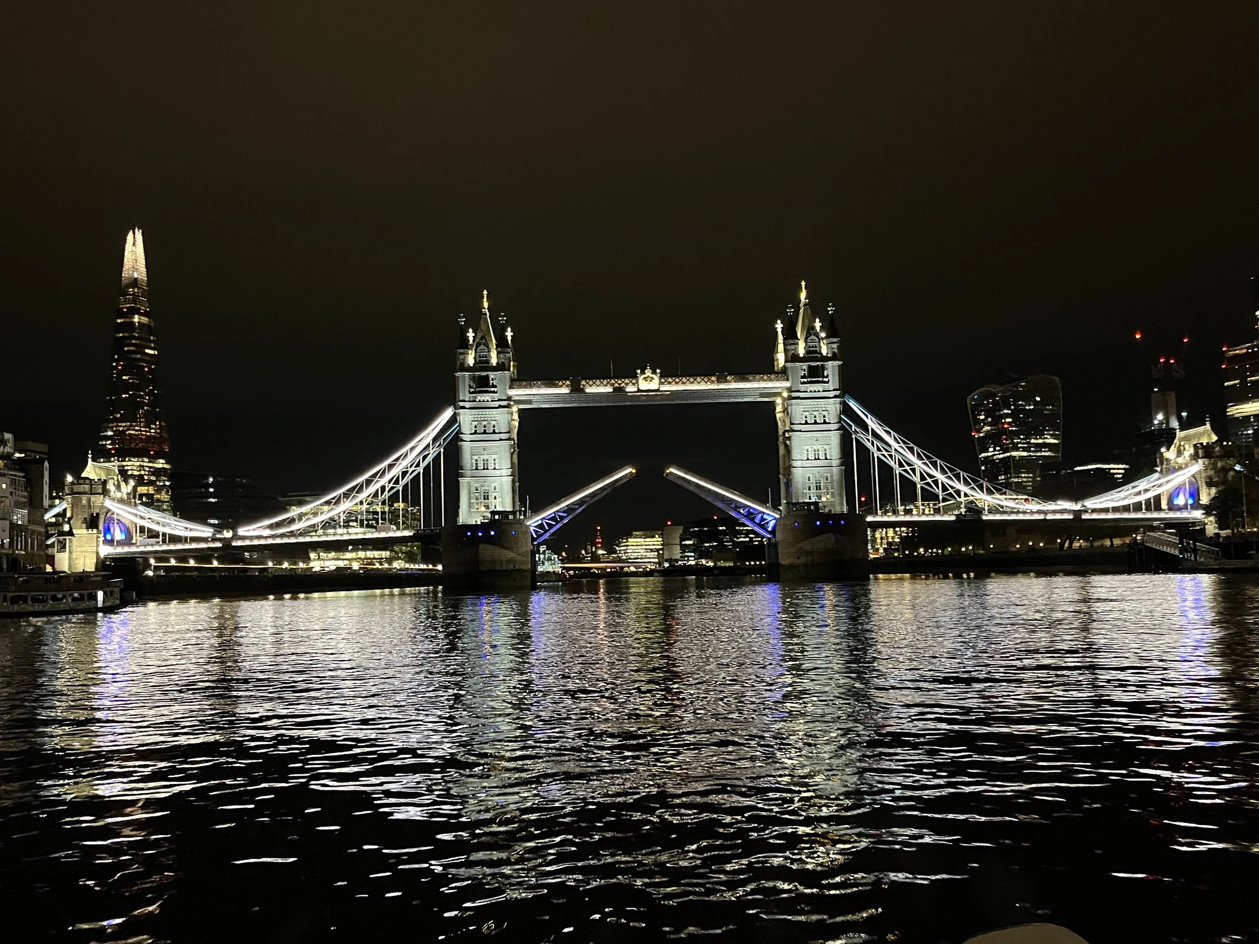 Night view of Tower Bridge in London, illuminated and reflected in the River Thames.