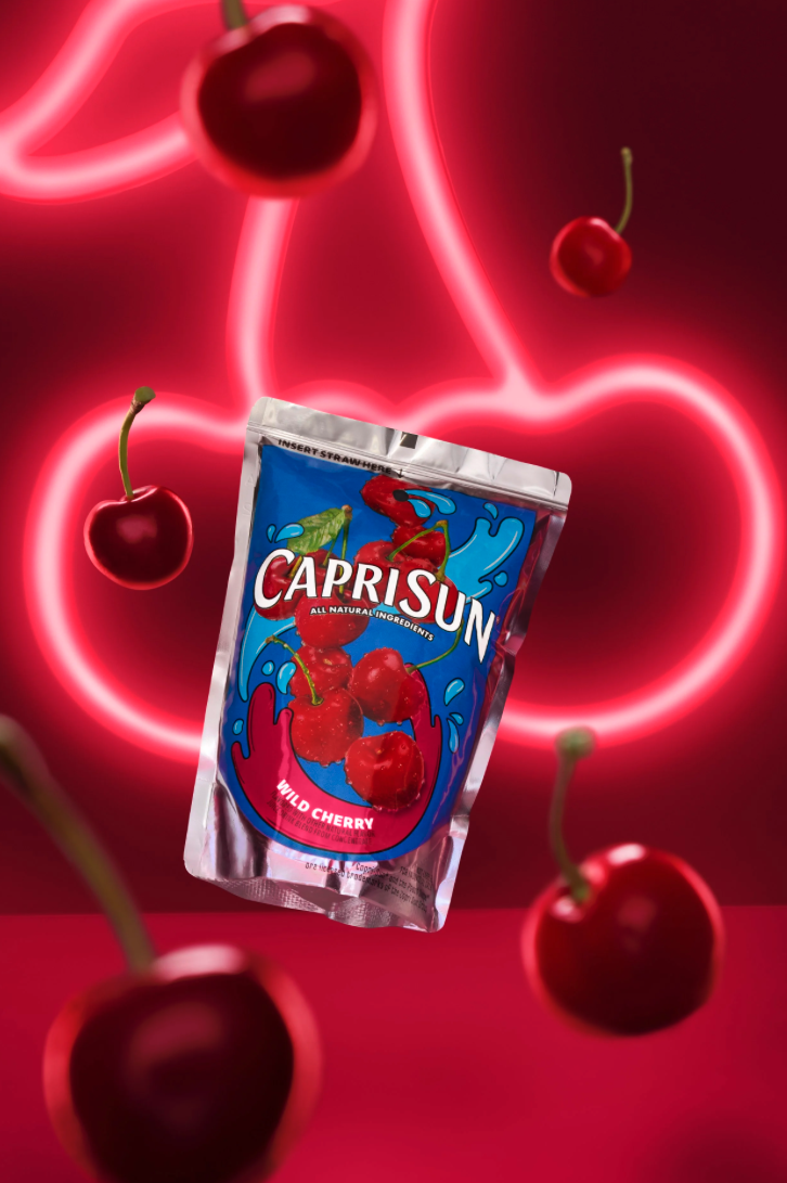A capri sun juice pouch is floating with a cherry shaped neon sign in the background and cherries floating around the juice pouch.