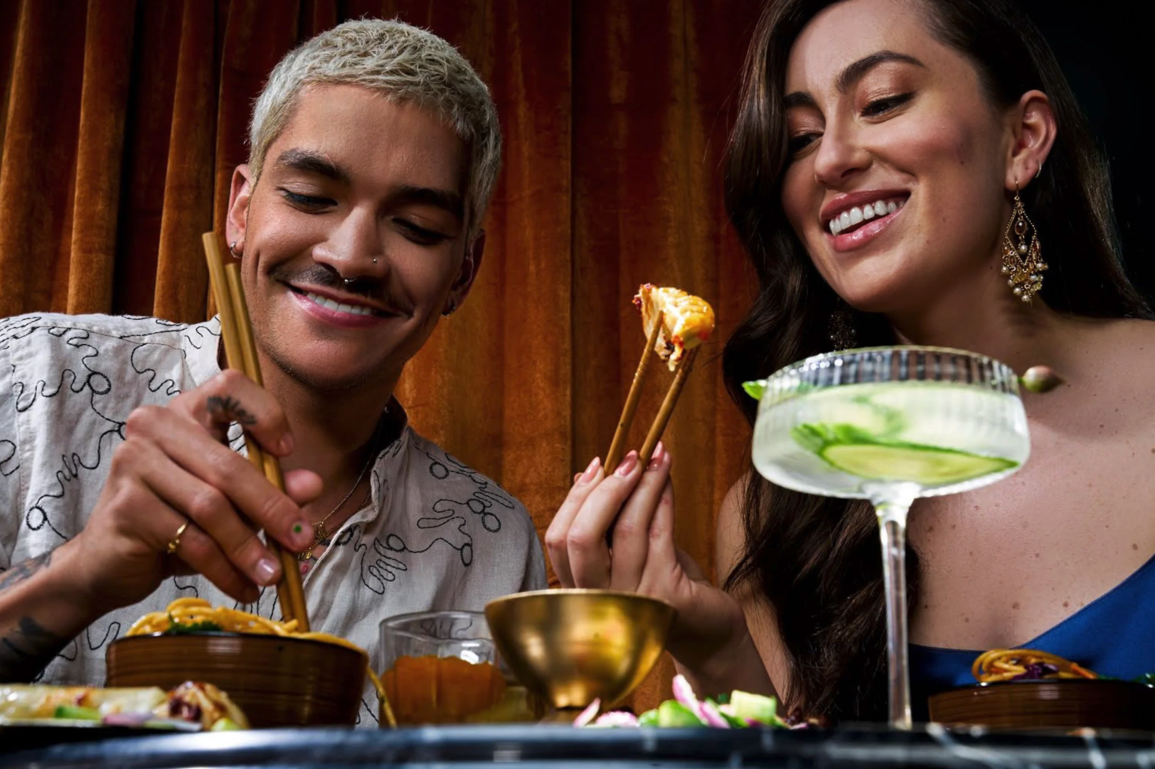 woman sitting at a table on a date in a restaurant. Eating asian food with chopsticks with candle light.