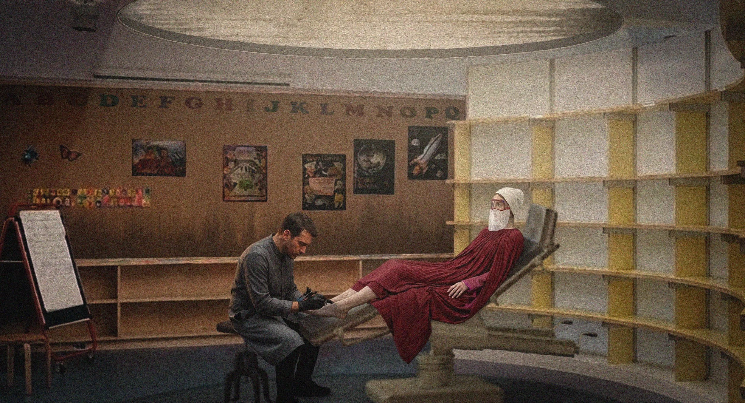 A person in a gray shirt and gloves kneels beside a mannequin in a red dress, appearing to examine or work on the mannequin's foot. The mannequin is seated in a chair, with a white beard, glasses, and head covering, in a room with shelves and posters