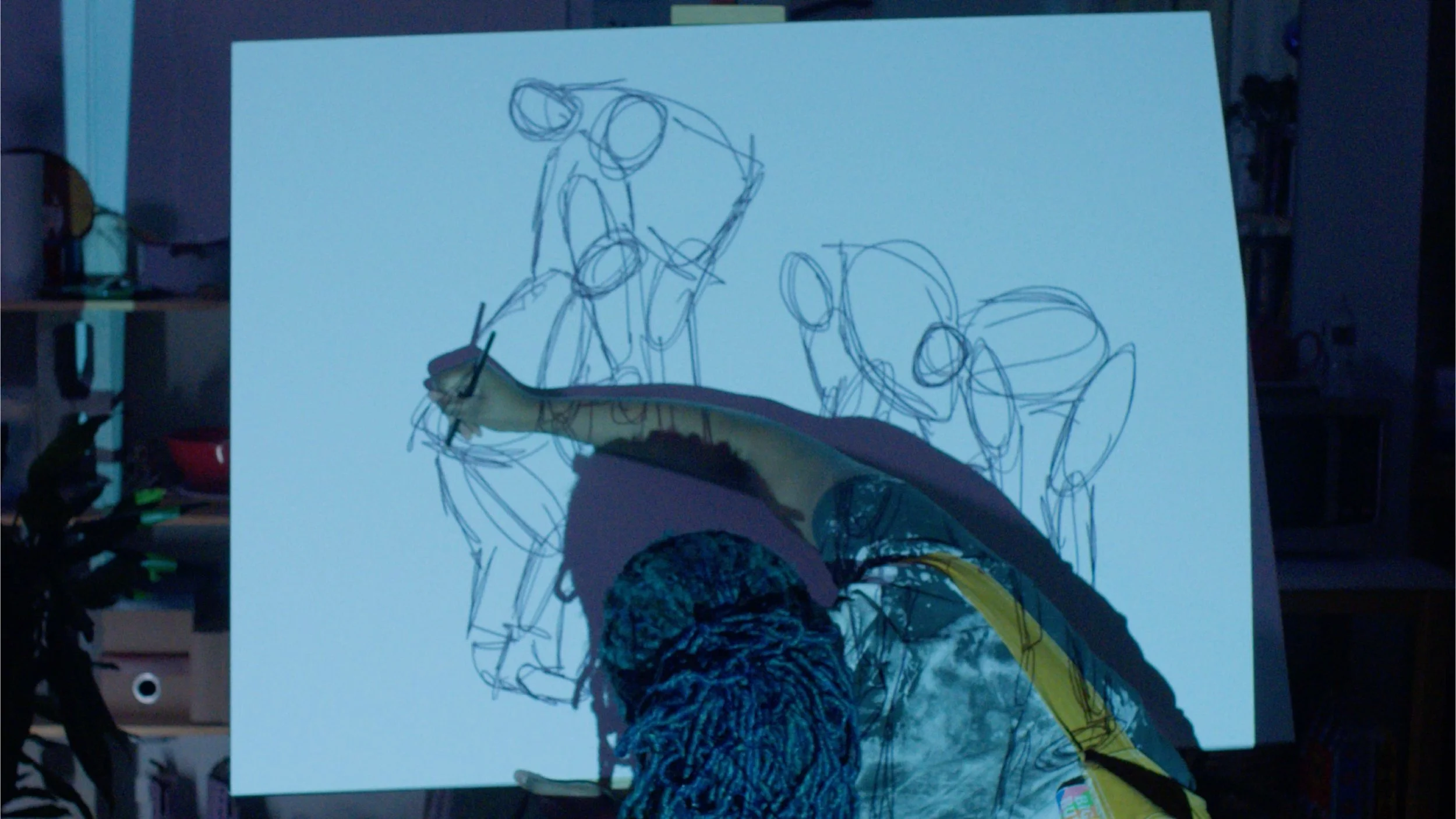 Artist sketching on a large sheet of paper depicting multiple figures with various poses.