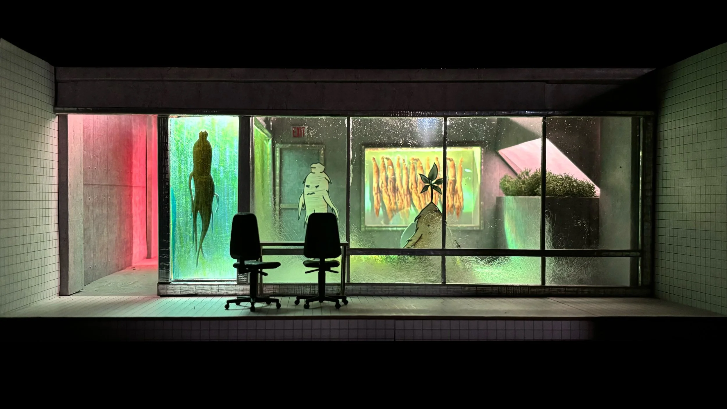 Indoor view through a large glass window featuring colorful, illuminated decorations. There are two black chairs facing the window, with silhouettes of abstract human figures and nature-themed artwork on the glass, including a leaf and a portrait with preserved plants.