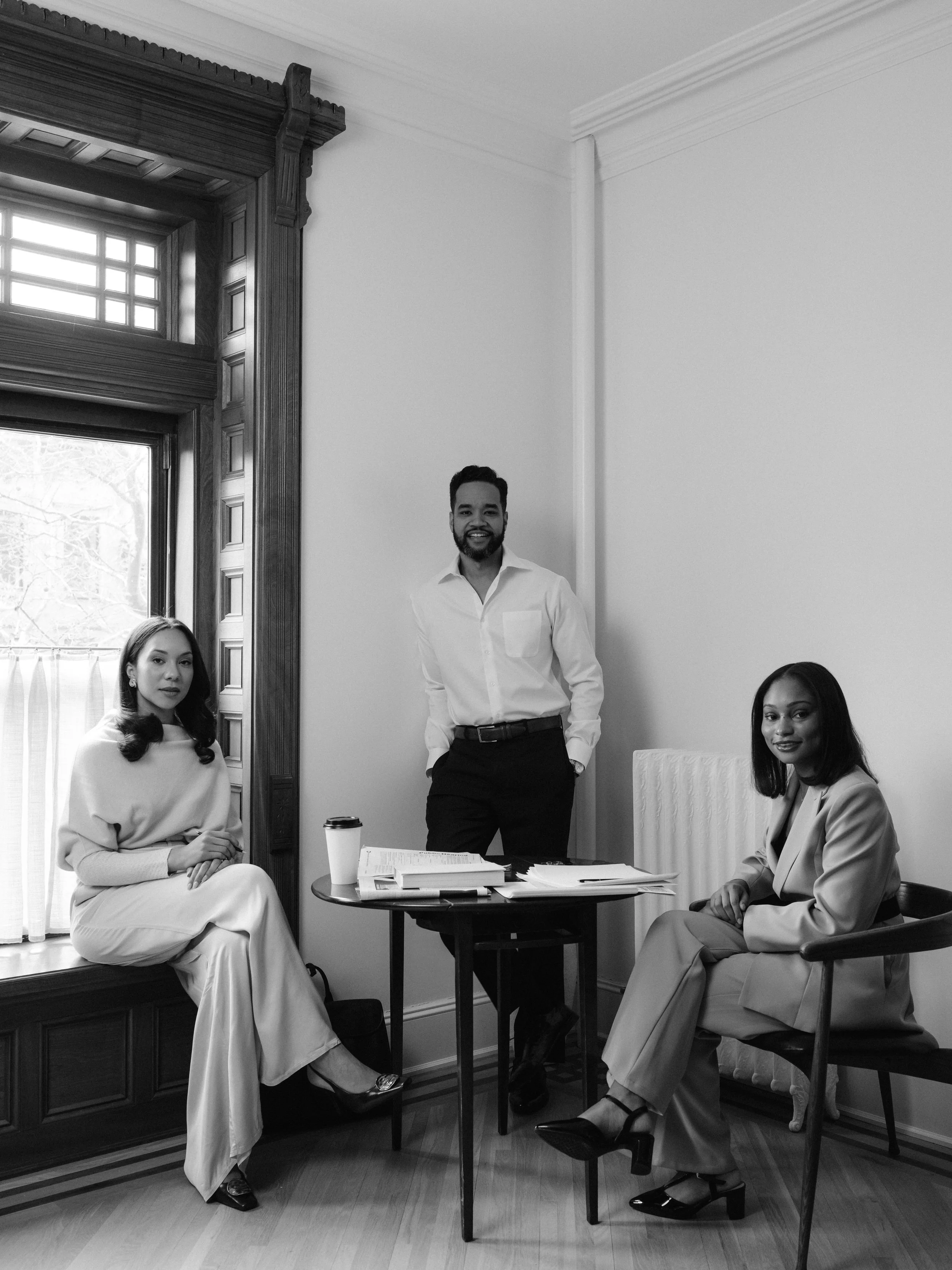 Three lawyers reviewing documents and drinking coffee at a corner table.