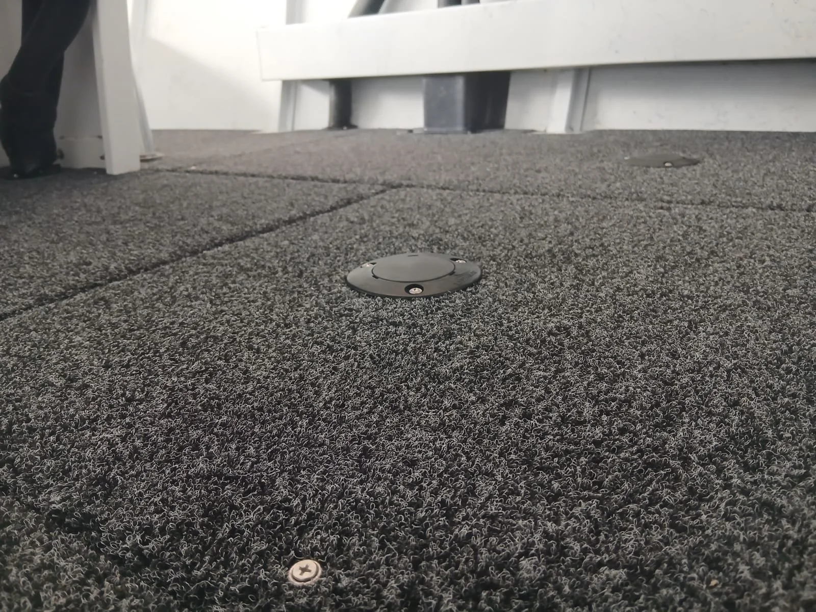 Close-up of a textured gray rooftop with multiple black and silver circular vents and small silver screws.