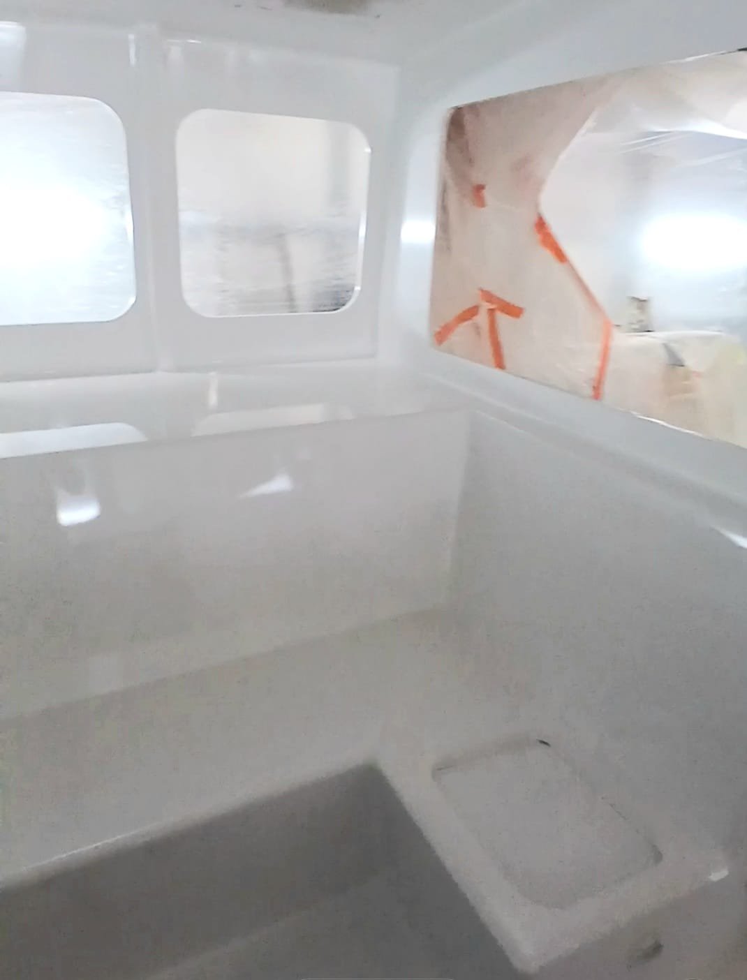 View inside a white refrigerator with empty shelves and a partially covered door shelf.