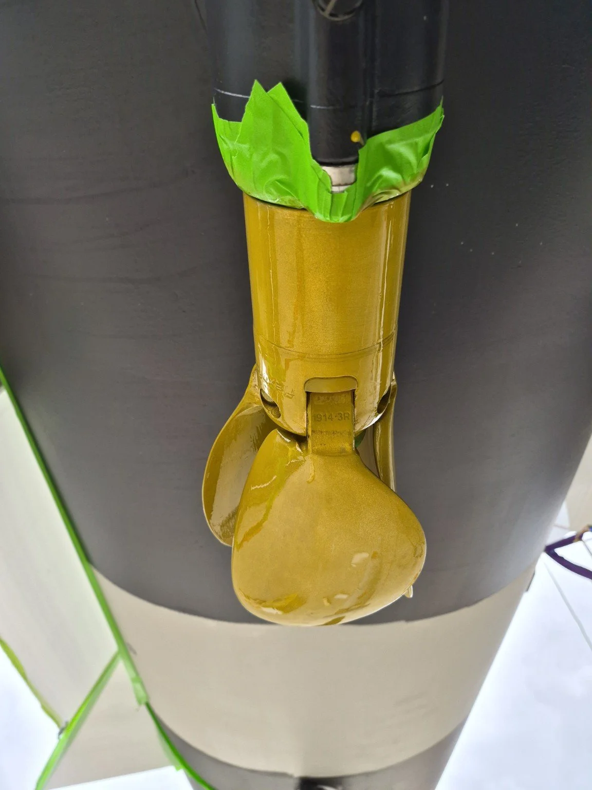 Marine saildrive with gold coating and green masking tape.