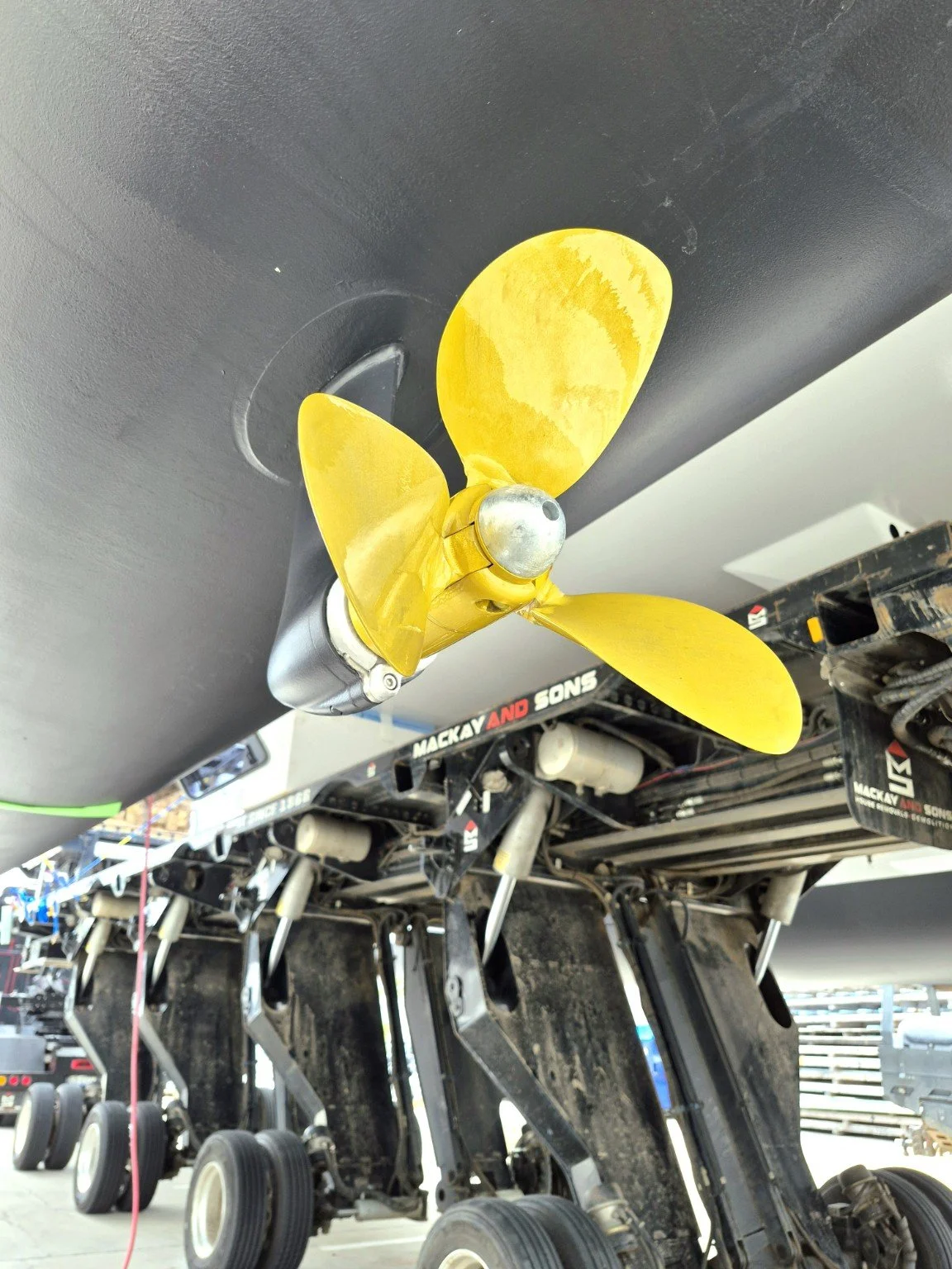 Gold-coated marine propeller beneath a boat hull.