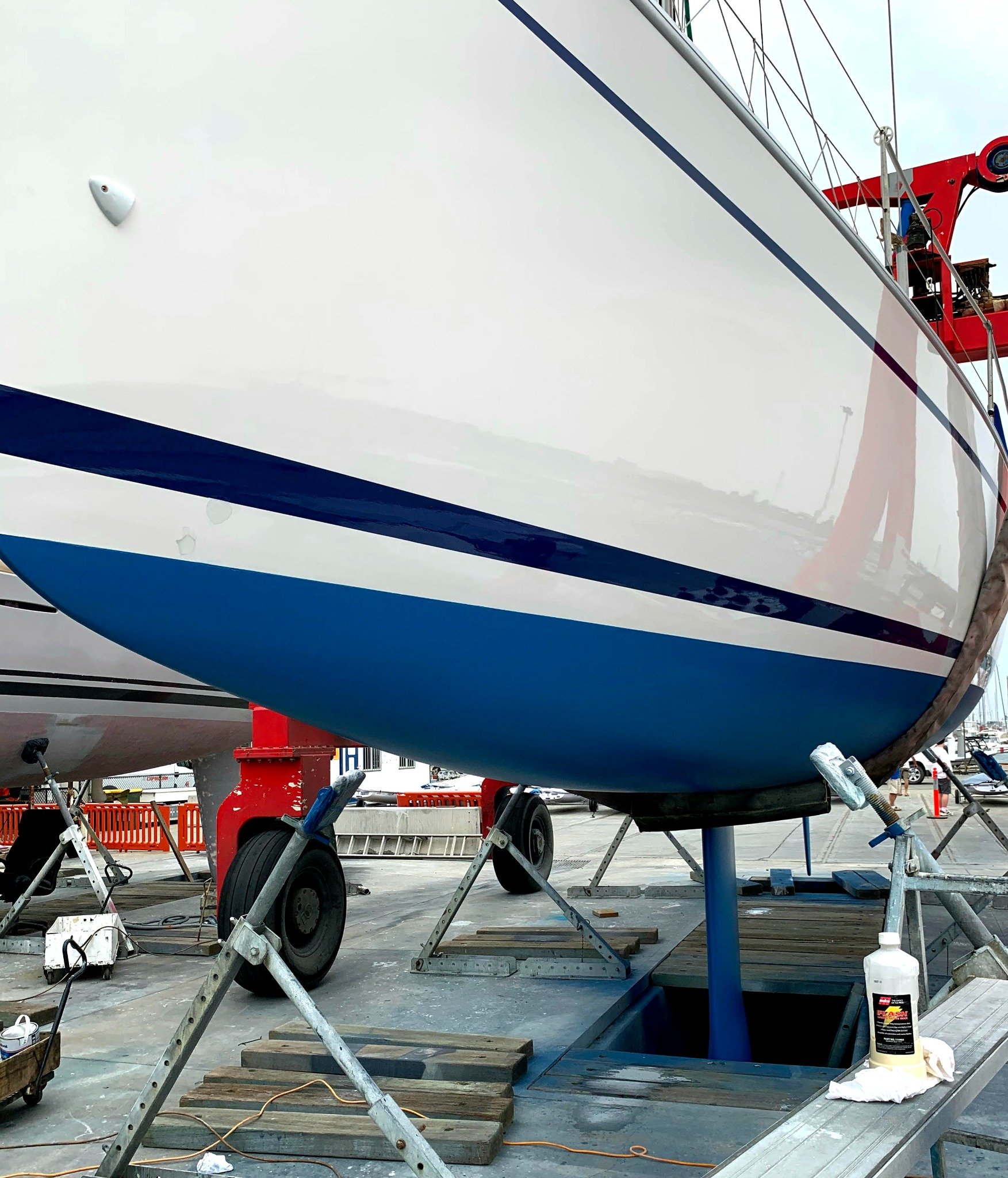 Polished yacht topsides with a wax bottle beside the hull.