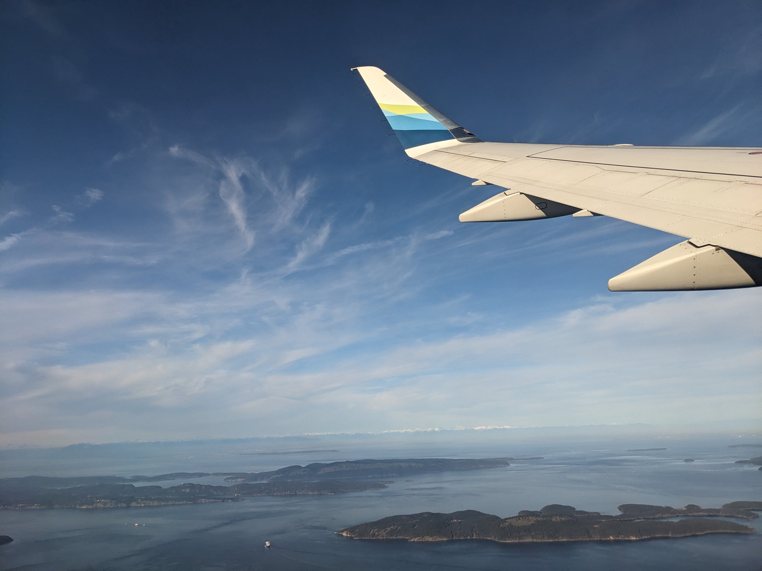 wing of a plane overlooking the ocean with several small islands.