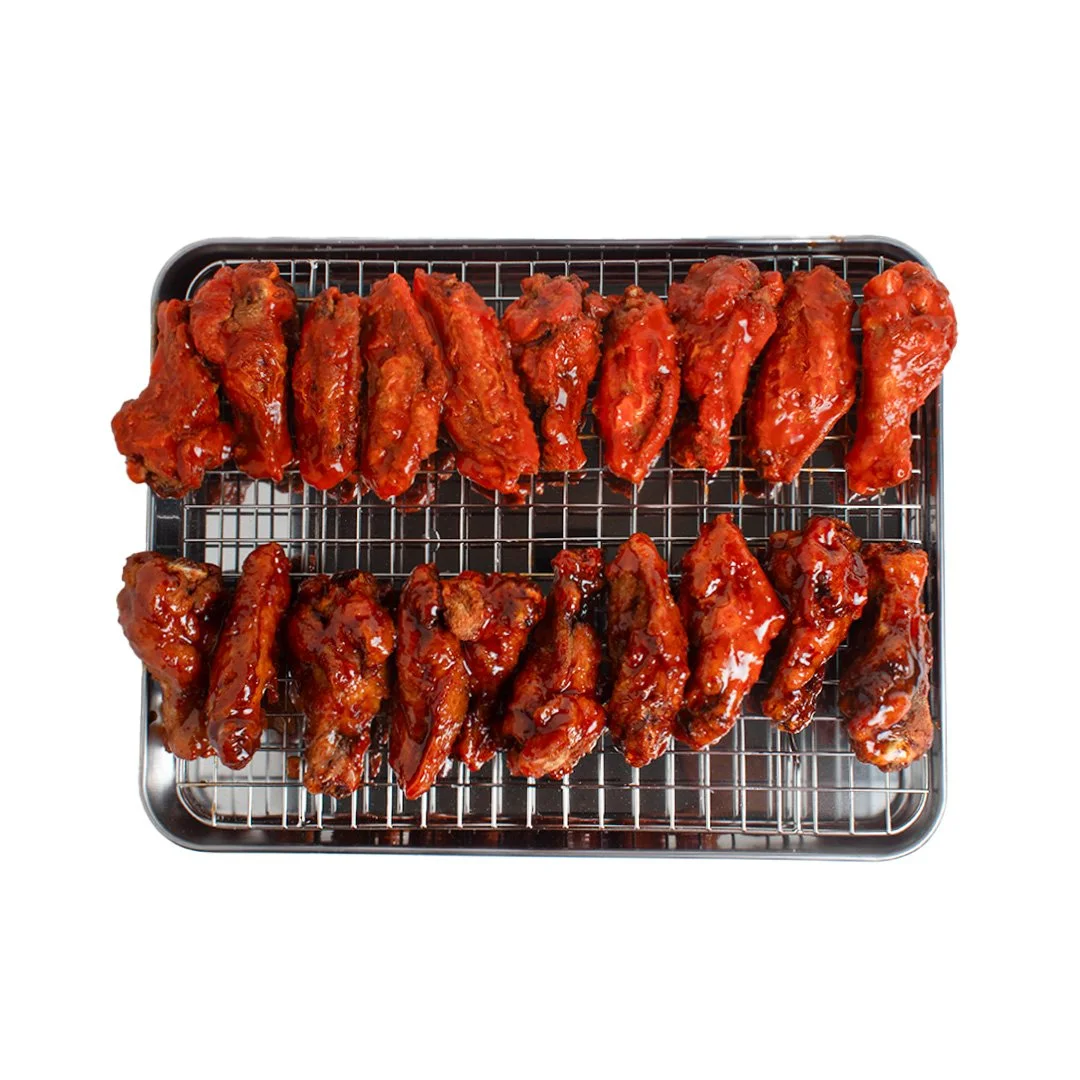 Tray of glazed chicken wings, featuring two rows of drumettes and wing pieces, on a wire rack.