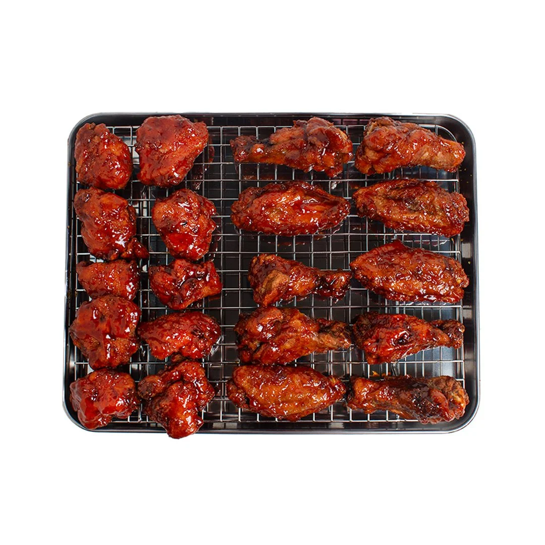 Baked chicken wings with barbecue sauce on a wire rack tray.