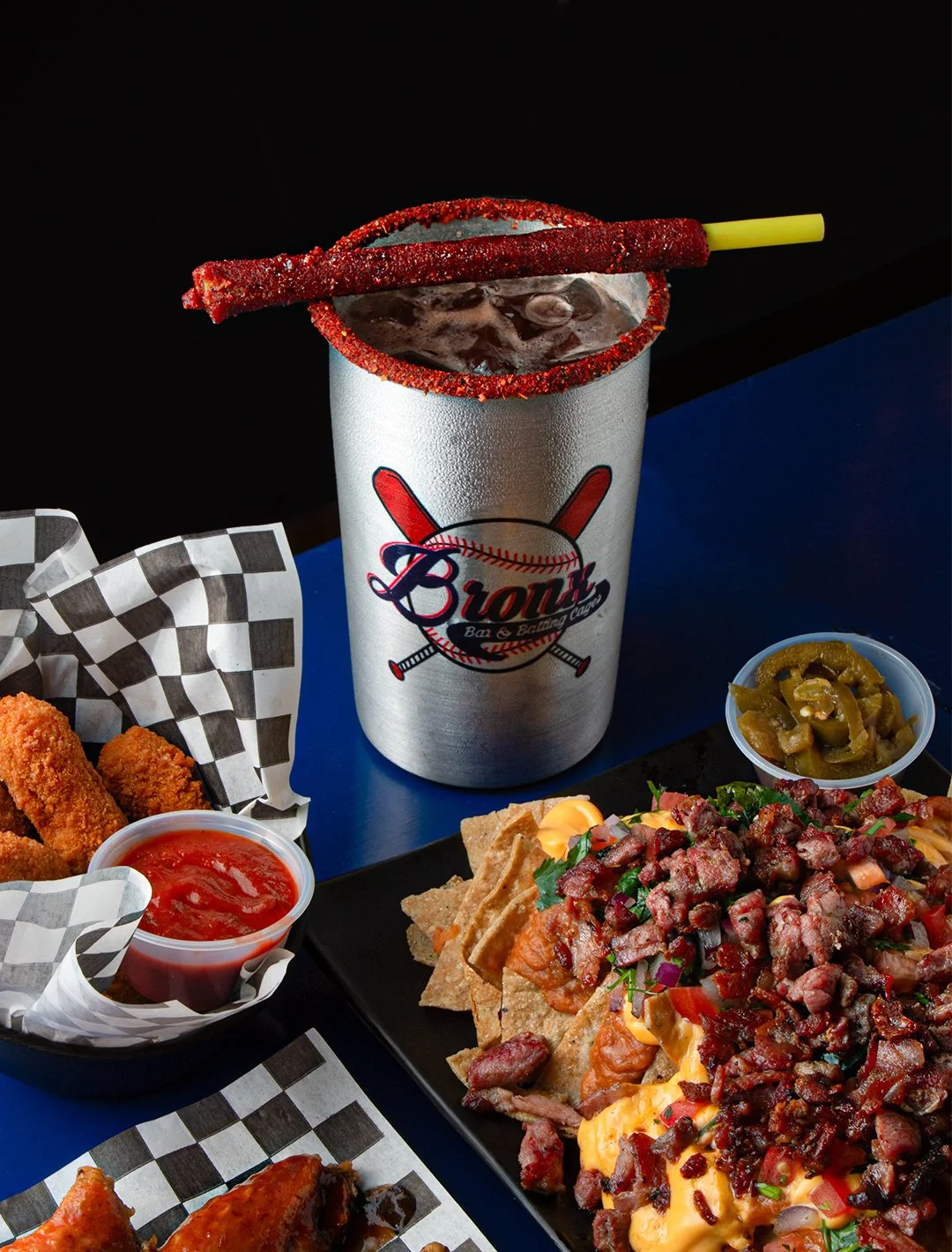 Barbecue and side dishes with a large soda in a metal cup, topped with a red sugar-coated breadstick