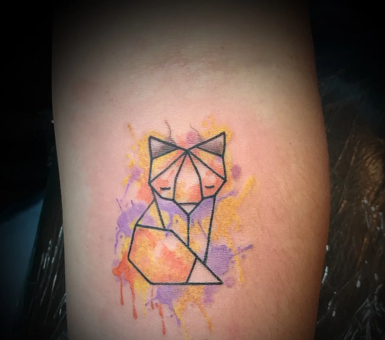 Tatouage géométrique d'un renard avec des éclaboussures de couleurs pastel comme le violet, le jaune, l'orange et le rose.