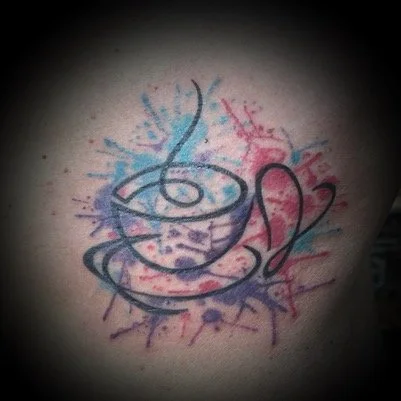Tatouage d'une tasse à café avec de la fumée colorée en arrière-plan.