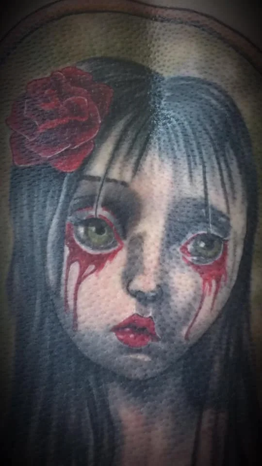 Tatouage d'une jeune fille avec des larmes rouges et un ruban rouge sur la tête.