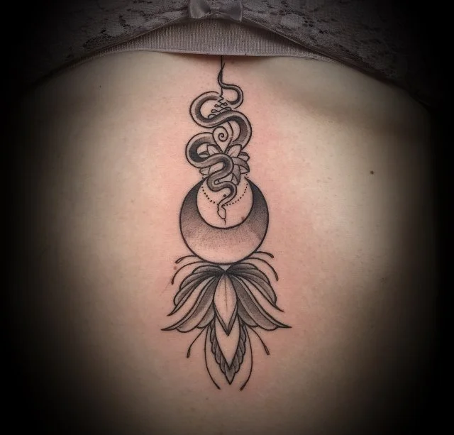 Tatouage noir et gris sur la peau, représentant une lune croissante, un serpent enroulé et une fleur stylisée