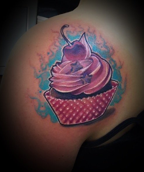 Tatouage d'une cupcake avec de la crème rose et une cerise sur le dessus, entourée de couleurs bleues et roses.