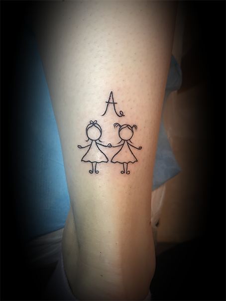 Tatouage d'une dessin simple de deux filles qui se tiennent la main, avec un grand 'A' au-dessus, sur le bras