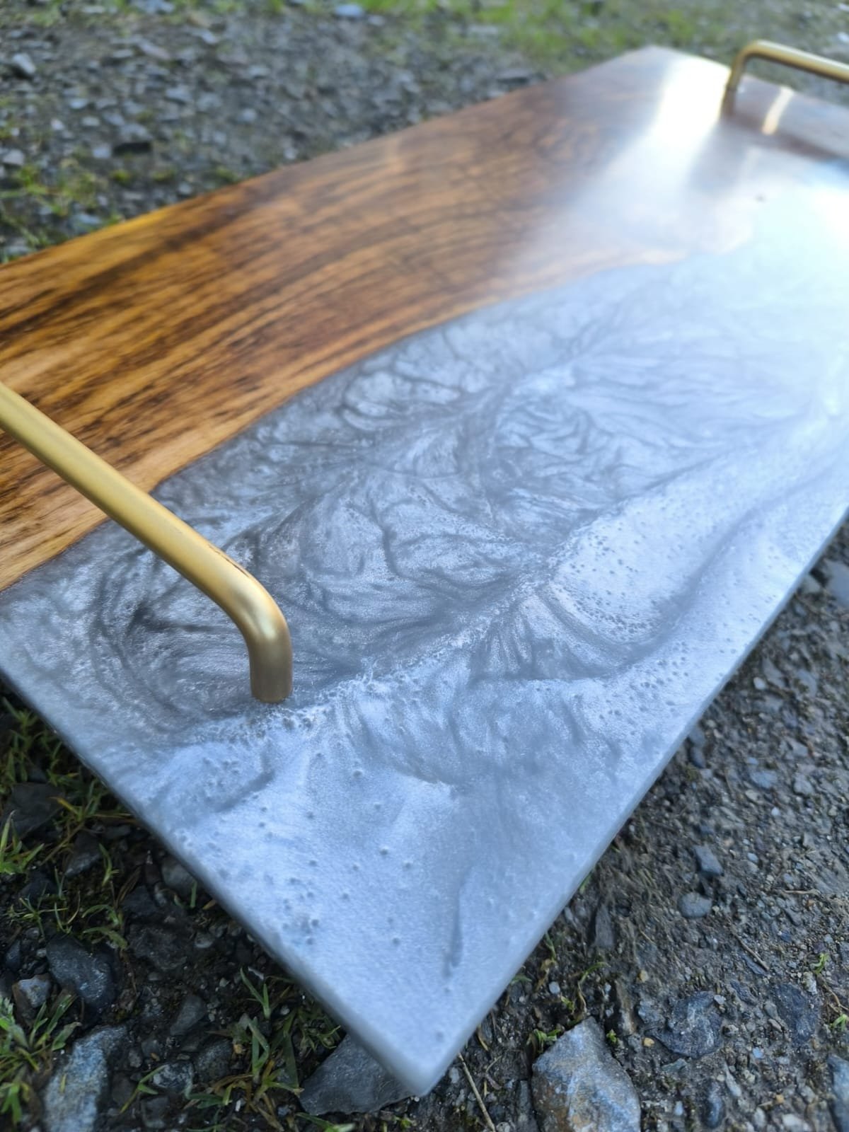 Table en bois avec surface en marbre gris, située à l'extérieur sur un sol rocheux.