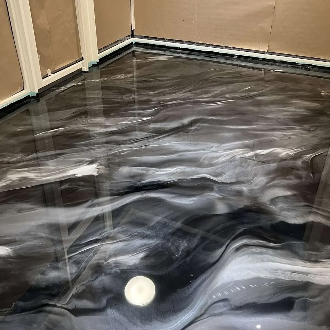 Sol en marbre noir et blanc avec des veines ondulantes, dans une pièce en construction.