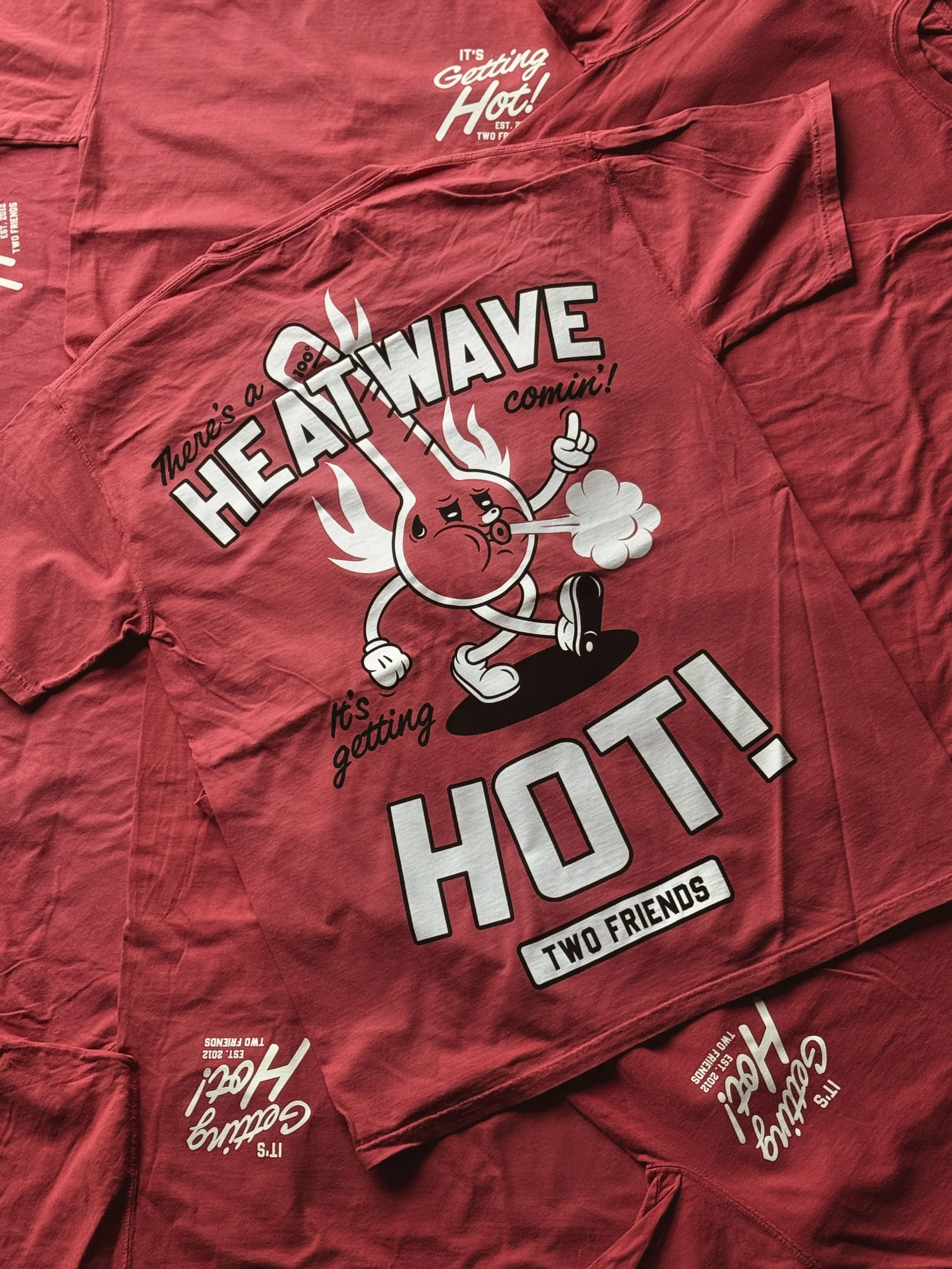 Red t-shirt with the text reading "It's Getting Hot!" and a cartoon of a hot chili pepper character with a thermometer in its mouth, conveying heat.