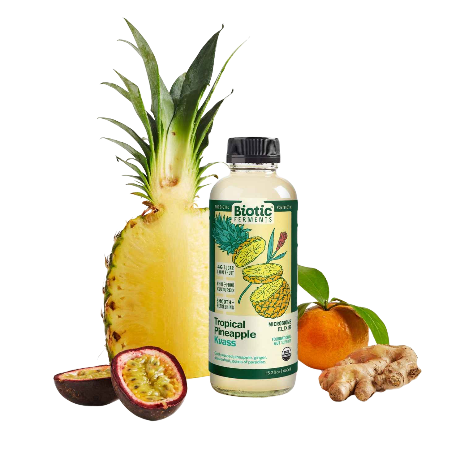 A bottle of Biotic Ferments Tropical Pineapple Kuass probiotic drink standing in front of a peeled pineapple, a halved passion fruit, an orange with leaves, and a piece of ginger root.